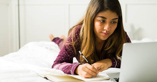 Young female student in a purple shirt looking at his laptop taking an online class at Connections Academy. 