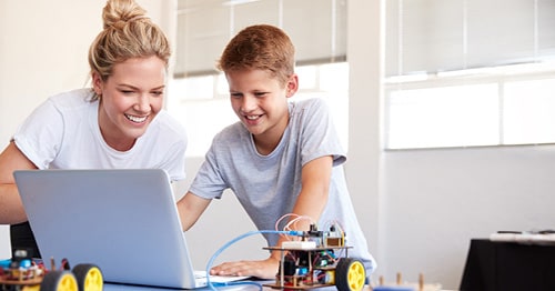 A middle school school student in a white shirt doing research towards an accredited online school like Connections Academy with their learning partner/mom.