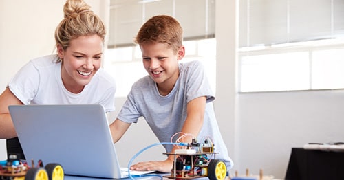 A middle school school student in a white shirt doing research towards an accredited online school like Connections Academy with their learning partner/mom. 