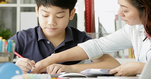 Image of a Learning Coach mom and her son working on an online assignment together. 