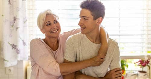 Learning Partner in a pale yellow shirt mom working with her teenage son in a white t shirt providing emotional support.