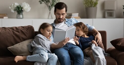 A parent encouraging his children to read over the summer by reading with them.