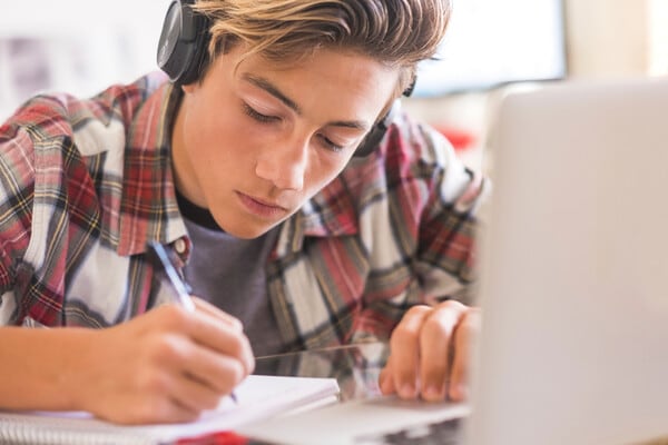 High shool boy taking notes at his desk