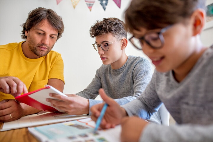 A parent helps his virtual school students with their homework on their own schedule