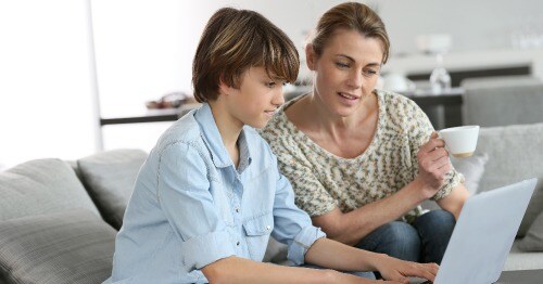 mother sitting with her middle school-aged child looking at an assignment on a computer