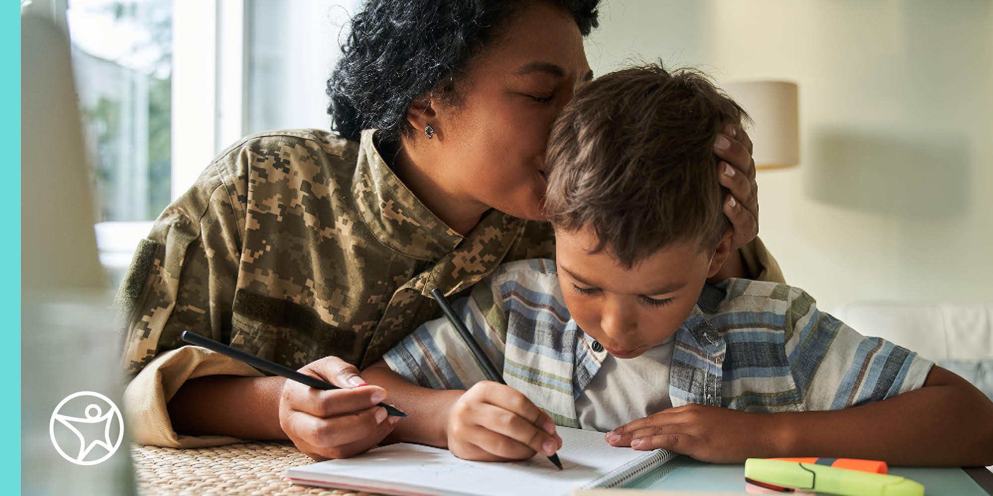 Mother kissing her sons head while he writes in a notebook - Connections Academy
