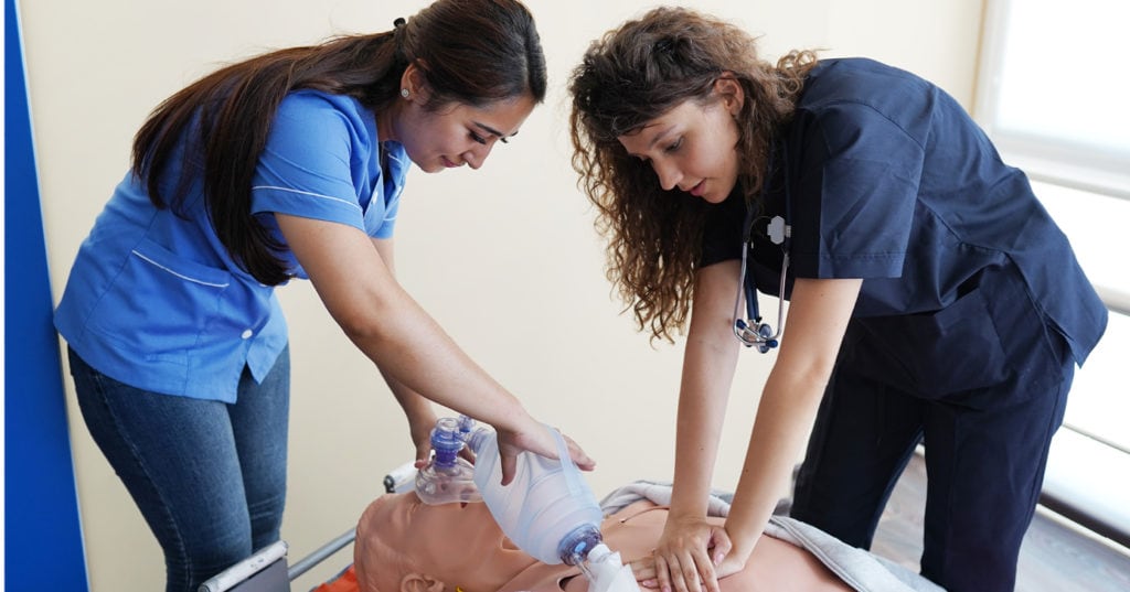 Two nursing students practicing CPR on a dummy