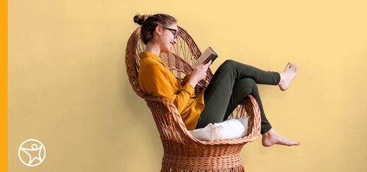 A teenage girl is sitting in a chair reading a book