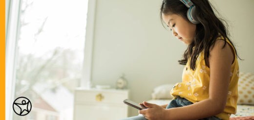 An elementary student wearing headphones and using her tablet