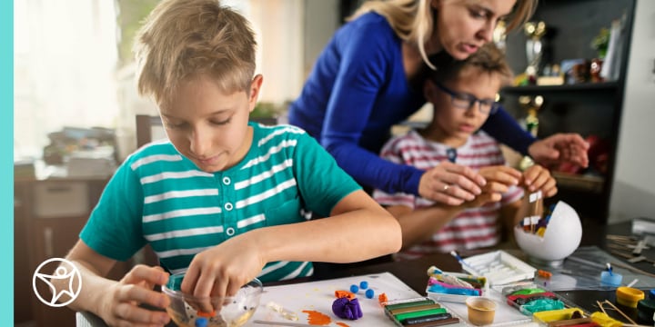 A mother helping two boys with a science craft