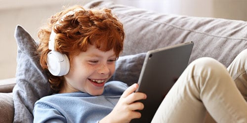 Young boy listens to music while reading to show how music helps students