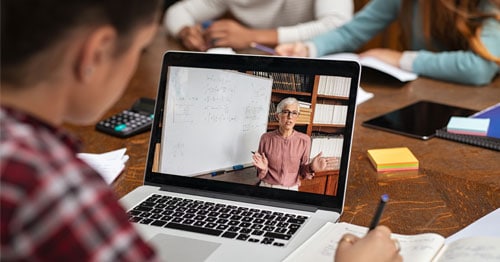 Young student watching on a laptop computer as an instructor teaches a virtual lesson