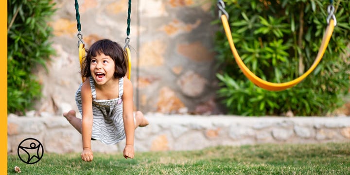 A kindergarten girl is playing on a swing