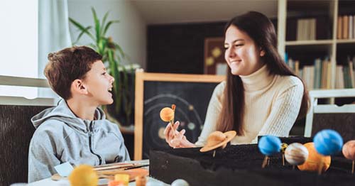 Mother working with middle school son on astronomy lesson and showing that online learning can be as effective as traditional