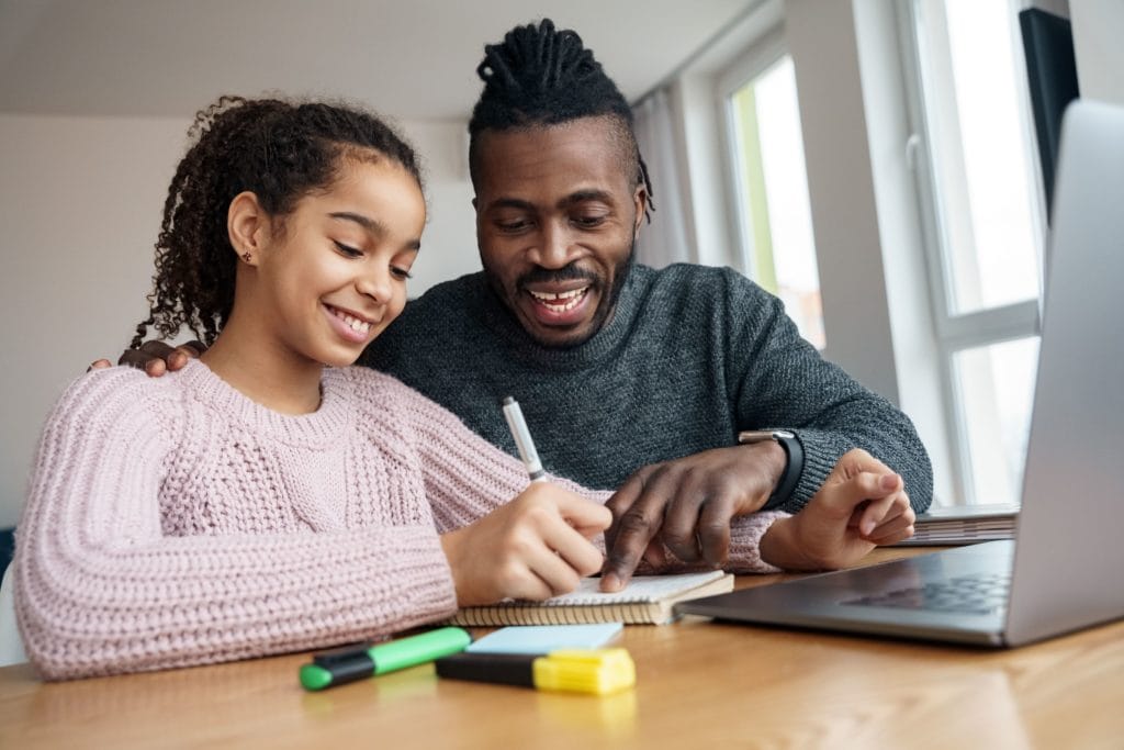 A father is helping his dauther take notes for an online class