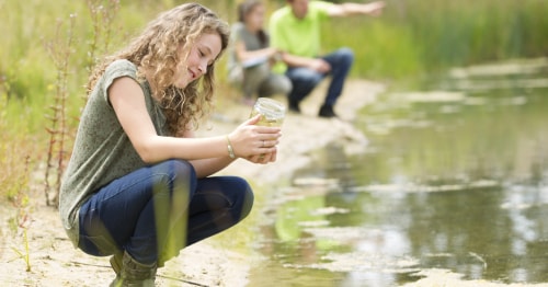 An online student on a field trip, looking at still water in a jar