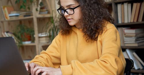 Online high school student works on dual credit program on her laptop to graduate from high school early