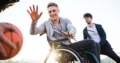 Male high school student in wheelchair plays pick-up basketball game demonstrating how peers are easily accessible in online school vs in person