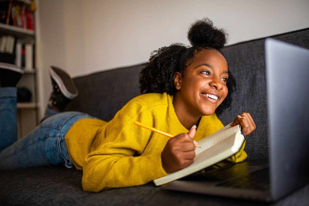 Young girl taking notes for her online class