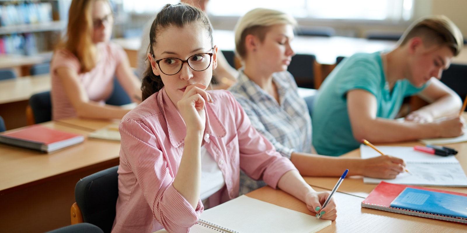 Young student sitting on coffee table doing schoolwork on her laptop
